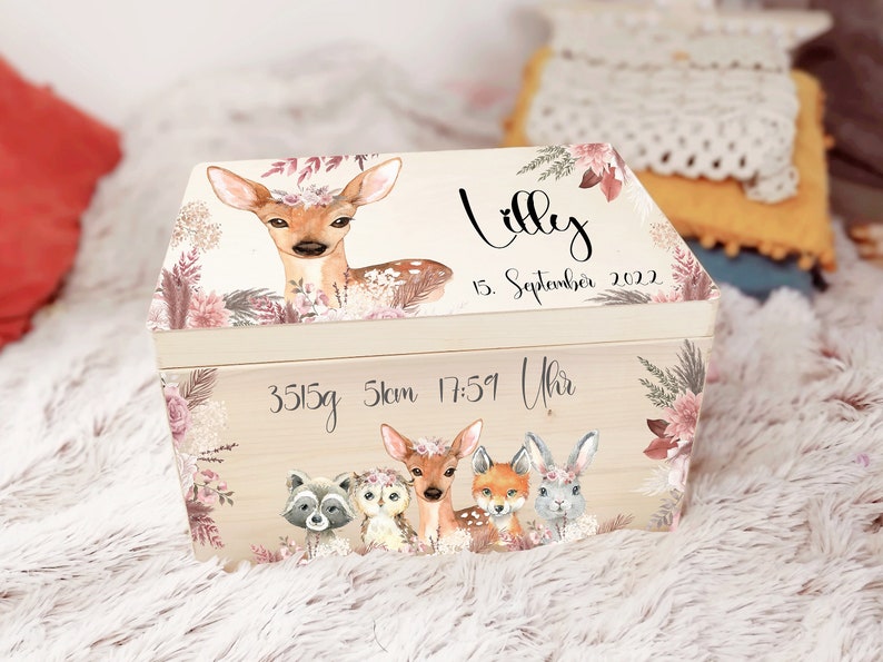 K&ouml;nnte beinhalten: Eine h&ouml;lzerne Erinnerungsbox mit einem Blumendesign und einem Reh auf dem Deckel. Die Box ist personalisiert mit dem Namen "Lilly", dem Datum "15. September 2022" und dem Text "3515g 51cm 17:51 Uhr".