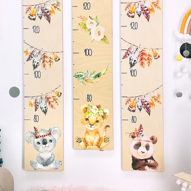 May include: Three wooden growth charts with animal illustrations and feather garlands. The charts feature a koala, a lion, and a panda, each with a headdress. The charts are marked with measurements in inches, from 80 to 120.