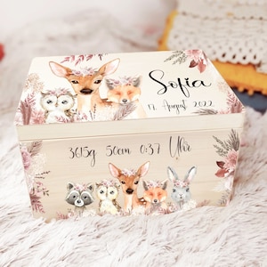 K&ouml;nnte beinhalten: Eine h&ouml;lzerne Erinnerungsbox mit hellbraunem Hintergrund und floralen Akzenten. Die Box zeigt eine fantasievolle Waldlandschaft mit einem Reh, einer Eule, einem Fuchs und einem Waschb&auml;r. Die Box ist personalisiert mit dem Namen "Sofia", dem Datum "17. August 2022" und den Geburtsdaten "3615g 50cm 0:37 Uhr".