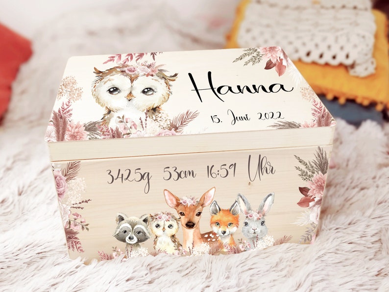 K&ouml;nnte beinhalten: Eine h&ouml;lzerne Erinnerungsbox mit floralem Design und Waldtieren. Die Box ist personalisiert mit dem Namen "Hanna", dem Datum "15. Juni 2022" und dem Text "3425g 53cm 16:51 Uhr".