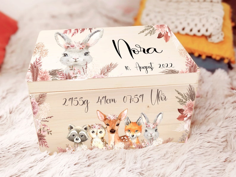 K&ouml;nnte beinhalten: Eine h&ouml;lzerne Erinnerungsbox mit floralem Design und einer Hasenillustration. Die Box ist personalisiert mit dem Namen "Nora", dem Datum "10. August 2022" und der Uhrzeit "07:51 Uhr". Die Box enth&auml;lt auch das Gewicht "2955g" und die L&auml;nge "41cm".