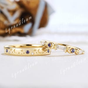 May include: Two gold rings with celestial designs. One ring features a band with crescent moons, stars, and small gemstones. The other ring has a row of gemstones and a baguette-cut stone, with moon and star accents.