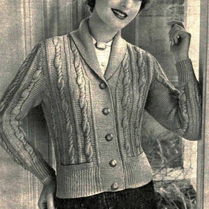 Peut inclure: Gros plan d'une femme portant un cardigan gris en tricot torsadé avec un col et une fermeture à boutons. Le cardigan a une poche sur le devant et est fait avec un fil épais.
