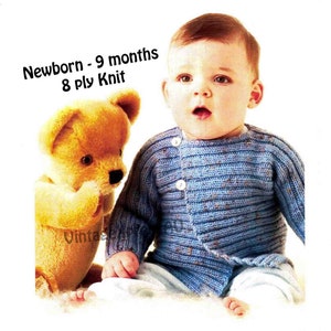 May include: A baby wearing a blue knitted cardigan with buttons. The cardigan is for newborns to 9 months old and is made with 8 ply knit. The baby is sitting with a teddy bear.