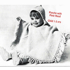 Peut inclure: Un poncho tricoté de couleur crème avec une capuche lutin, porté par un enfant. Le poncho a une bordure à franges. Le texte "Poncho with Pixie Hood Child 1-3 yrs" est en rouge. L'enfant porte des chaussures blanches.