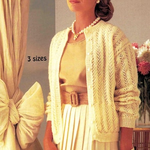 May include: A woman wearing a light yellow cardigan with a pearl necklace and bracelet. The cardigan has a button-up front and a textured pattern. The outfit includes a matching skirt and belt. The text "3 sizes" is visible.
