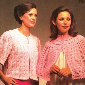 May include: Two women modeling pink crocheted garments. One wears a short-sleeved cardigan with a leaf-like pattern and button closure. The other wears a cape with a scalloped edge and button closure. The garments are a light pink color.