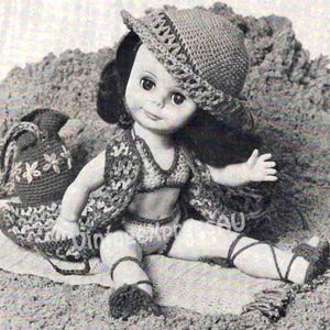 May include: A vintage doll wearing a crocheted outfit, including a hat, vest, bikini top, and shorts. The doll is seated on a sandy surface, with a crocheted bag nearby. The outfit is in a neutral color palette.