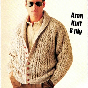 May include: A beige Aran knit cardigan with a shawl collar and button closure. The cardigan is made of 8 ply yarn and features a cable knit pattern.