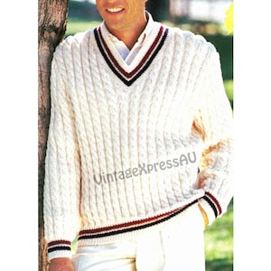 May include: Cream-colored cable knit sweater with a V-neck and striped trim in navy, burgundy, and cream. The sweater has long sleeves and is a classic style. The text "VintageXpressAU" is visible on the sweater.