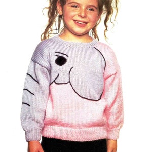 Op de afbeelding: Een gebreide kindertrui met een olifantenontwerp. De trui loopt van lichtpaars naar roze. Het gezicht van de olifant is zwart omlijnd, met een zwart oog. De mouwen en zoom zijn geribbeld.