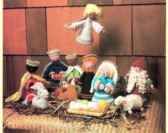 May include: A crocheted nativity scene featuring a white angel, three wise men, Mary, Joseph, baby Jesus, and two sheep. The figures are all handmade and have a rustic, vintage appearance.