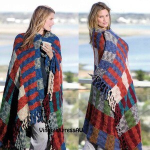 May include: A colorful knitted throw blanket with fringe. The blanket is made of a variety of colors, including red, blue, green, and white. The blanket is draped over a person's shoulders.