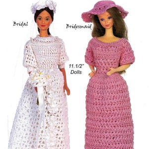 May include: Two dolls, labelled "Bridal" and "Bridesmaid", are dressed in crocheted gowns. The bridal doll wears a white dress with a matching headpiece and carries a bouquet. The bridesmaid doll is in a pink dress and hat. The dolls are 29.2 cm tall.