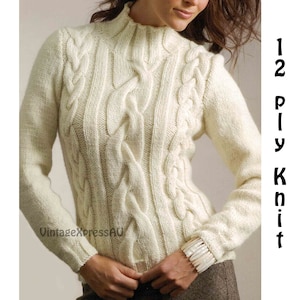 May include: A white cable knit sweater with a high neck and long sleeves. The sweater is made of a thick yarn and has a textured pattern.