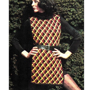 Peut inclure: Une robe noire sans manches avec un motif géométrique rouge, jaune et noir. La robe est ceinturée à la taille avec une ceinture en cuir noir.