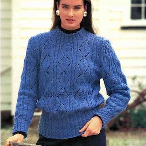 Könnte beinhalten: Ein blauer Strickpullover mit Rautenmuster und einem hohen Kragen.