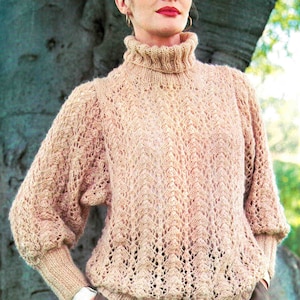 May include: A light brown knitted sweater with a high neck and a lacy pattern. The sweater has long sleeves and a relaxed fit.