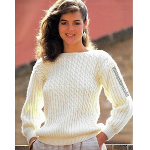 May include: A white knitted sweater with a cable knit pattern. The sweater has a round neckline and long sleeves.