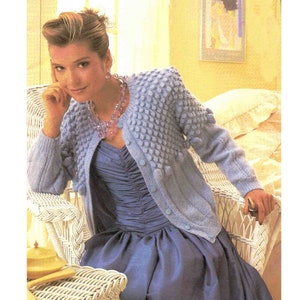 May include: A light blue knitted cardigan with a textured, bobbly design. The cardigan has a button-up front and long sleeves.