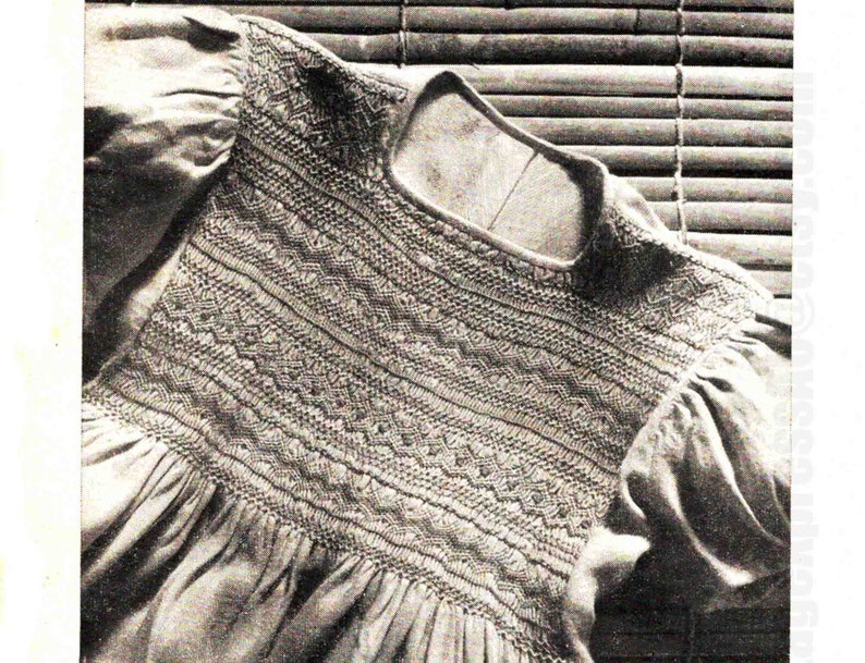 May include: A close-up of a white garment with a detailed embroidered neckline. The embroidery is done in a variety of stitches, creating a textured and intricate design.