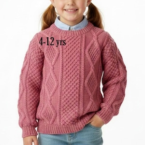 May include: A dusty rose long-sleeve cable knit jumper with a crew neckline and ribbed cuffs and hem. The jumper features a textured diamond and vertical pattern throughout. The text 4-12 yrs is printed on the front of the garment.