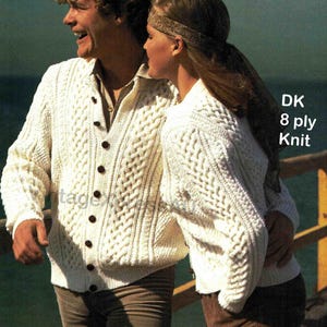 Op de afbeelding: Twee witte kabelgebreide truien, een cardigan en een ronde hals, met een DK 8 draads breietiket.