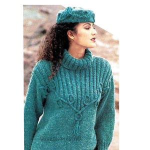 May include: A teal blue knitted sweater with a turtleneck and a decorative cable knit design. The sweater has a tassel detail at the bottom.