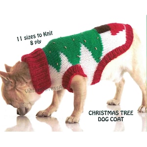 May include: A small dog wearing a knitted Christmas tree dog coat. The coat is red, white and green with a brown star on the top. The dog is looking down at the ground.