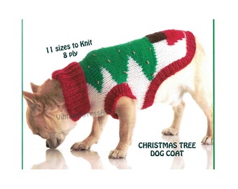 May include: A small dog wearing a knitted Christmas tree dog coat. The coat is red, white, and green with a brown star on the top. The dog is looking down at the ground.
