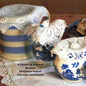 May include: A collection of ceramic containers, including a large jar with blue stripes and smaller blue and white patterned pots, all adorned with delicate white crochet covers. The image also features a plate with baked goods and the text: "4 Covers to Crochet Beaded Miniature Teapot Tiny Cup and Saucer."