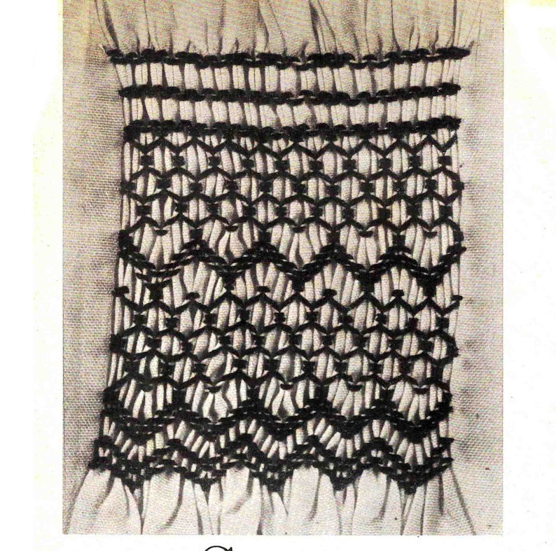 May include: A close-up of a white fabric with a black embroidered design. The design features a series of interlocking diamonds and a scalloped edge.