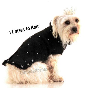 Può includere: Un piccolo cane bianco che indossa un maglione nero lavorato a maglia con accenti di glitter argentati. Il maglione ha un bordo arricciato. Il cane indossa una corona e il testo "11 taglie da lavorare a maglia" è visibile nell'immagine.