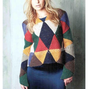 Puede incluir: Un suéter colorido con estampado geométrico y mangas largas. El suéter presenta un diseño de patchwork de varios colores, incluyendo rojo, azul, verde, amarillo y marrón. La prenda se usa sobre una blusa azul oscuro.