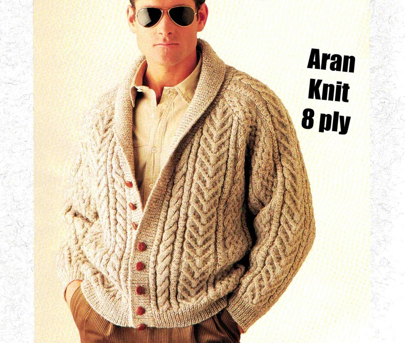 May include: A beige Aran knit cardigan with a shawl collar and button closure. The cardigan has a cable knit pattern and is made of 8 ply yarn.