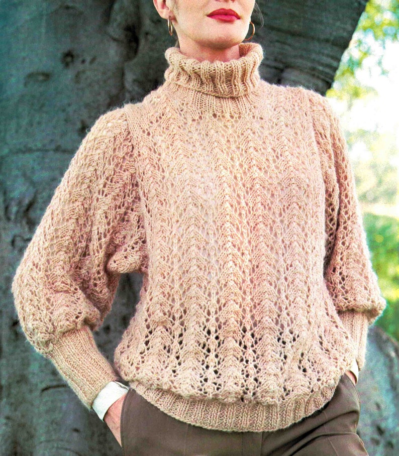 May include: A light brown knitted sweater with a high neck and a lacy pattern. The sweater has long sleeves and a relaxed fit.
