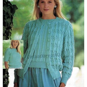 May include: A light blue knitted cardigan and matching crew neck sweater. The cardigan has a button-up front and intricate openwork detailing. The sweater has a ribbed design. The image also includes a smaller image of a similar sweater.