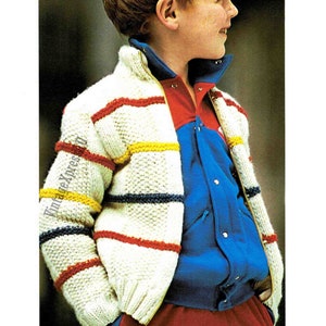 May include: A white knitted cardigan with a zipper closure and colorful stripes in red, yellow, and blue. The cardigan is worn over a blue button-up shirt and red pants.
