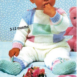 Peut inclure: Un ensemble tricoté pour bébé composé d'un pull et d'un pantalon avec un motif patchwork aux couleurs pastel, notamment blanc, bleu, vert et rose. Le pull présente des manches longues avec des poignets côtelés et un col rond. Le texte 3-12 months est imprimé.
