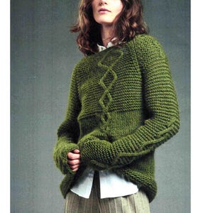 May include: A green knit sweater with a diamond pattern on the front. The sweater has long sleeves and a ribbed hem and cuffs. The model is wearing a white collared shirt underneath.
