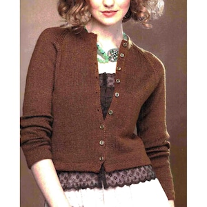 May include: A brown button-down cardigan. The long-sleeved sweater has a ribbed texture and is worn over a dark top with lace trim. The buttons are brown. A classic style of cardigan.