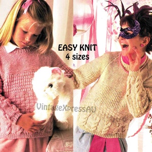 May include: Two girls wearing knitted sweaters. The girl on the left is holding a white stuffed animal. The girl on the right is wearing a mask and a pink headband. The text "EASY KNIT 4 sizes" is printed on the image.