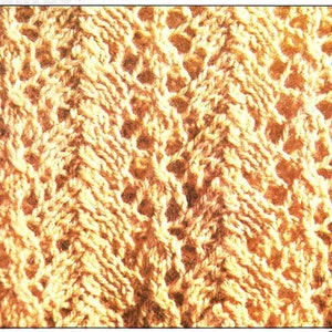 May include: Close-up of a knitted fabric with a textured pattern. The fabric is a light beige color and has a repeating pattern of small holes.