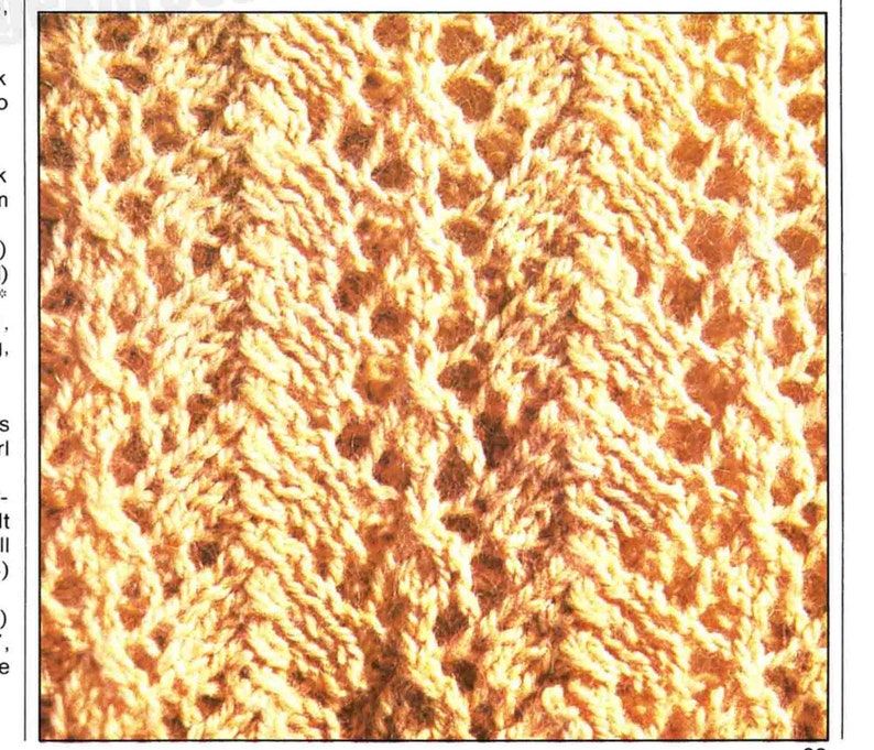 May include: Close-up of a knitted fabric with a textured pattern. The fabric is a light beige color and has a repeating pattern of small holes.