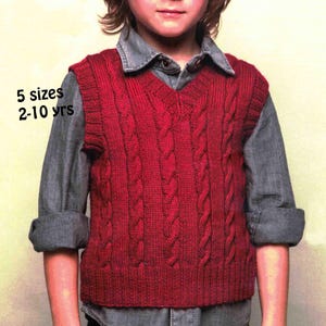 May include: A red cable-knit vest with a V-neck, worn over a grey button-down shirt. The vest has a textured pattern and is designed for children aged 2-10 years old, available in 5 sizes. The text "5 sizes 2-10 yrs" is visible.