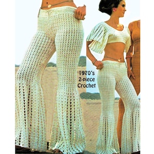 May include: A two-piece crochet set consisting of a white cropped top with wide sleeves and matching flared trousers. The set features an open-work pattern and is labeled 1970's 2-piece Crochet. The design includes a thin waist chain accessory.