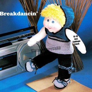 Puede incluir: Patrón de crochet para una muñeca breakdance, con un atuendo con capucha azul y gris y pantalones negros. La muñeca mide de 38 a 46 cm de alto y se muestra posando con una radiograbadora.