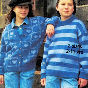 May include: Two children wearing blue knitted sweaters. The girl's sweater has a heart pattern and the boy's sweater has blue and white stripes. The text on the boy's sweater says "7 sizes 2-14 yrs".