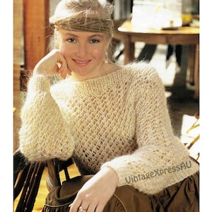 May include: A cream knitted jumper with a loose, open-weave pattern. The jumper has long sleeves and a round neckline.