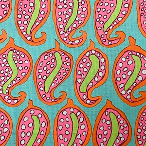 May include: A turquoise fabric with a repeating pattern of pink and white paisley shapes outlined in orange. The paisley shapes have green accents.
